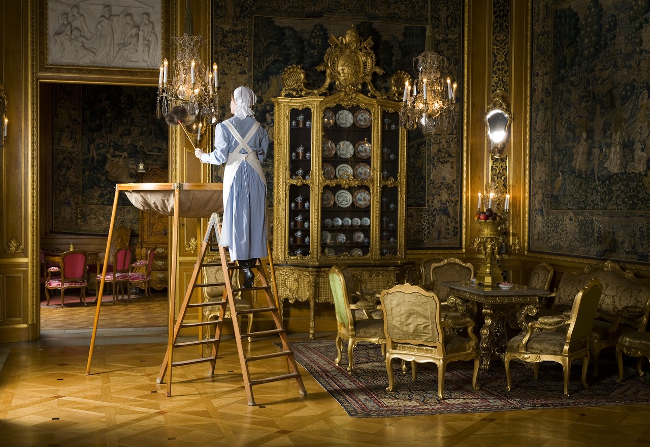 Image of 18th century maid cleaning chandelier in mansion