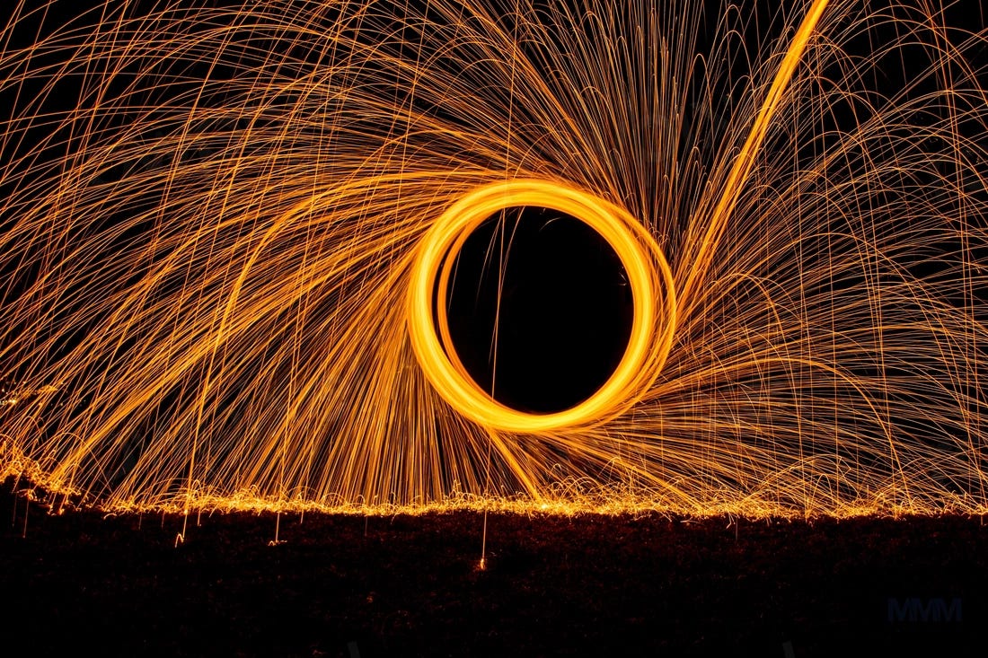 graphic image of bright orange circle with numerous light strands around it