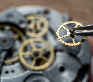 Gears in a mechanical watch with workman's tweezers holding a small gear