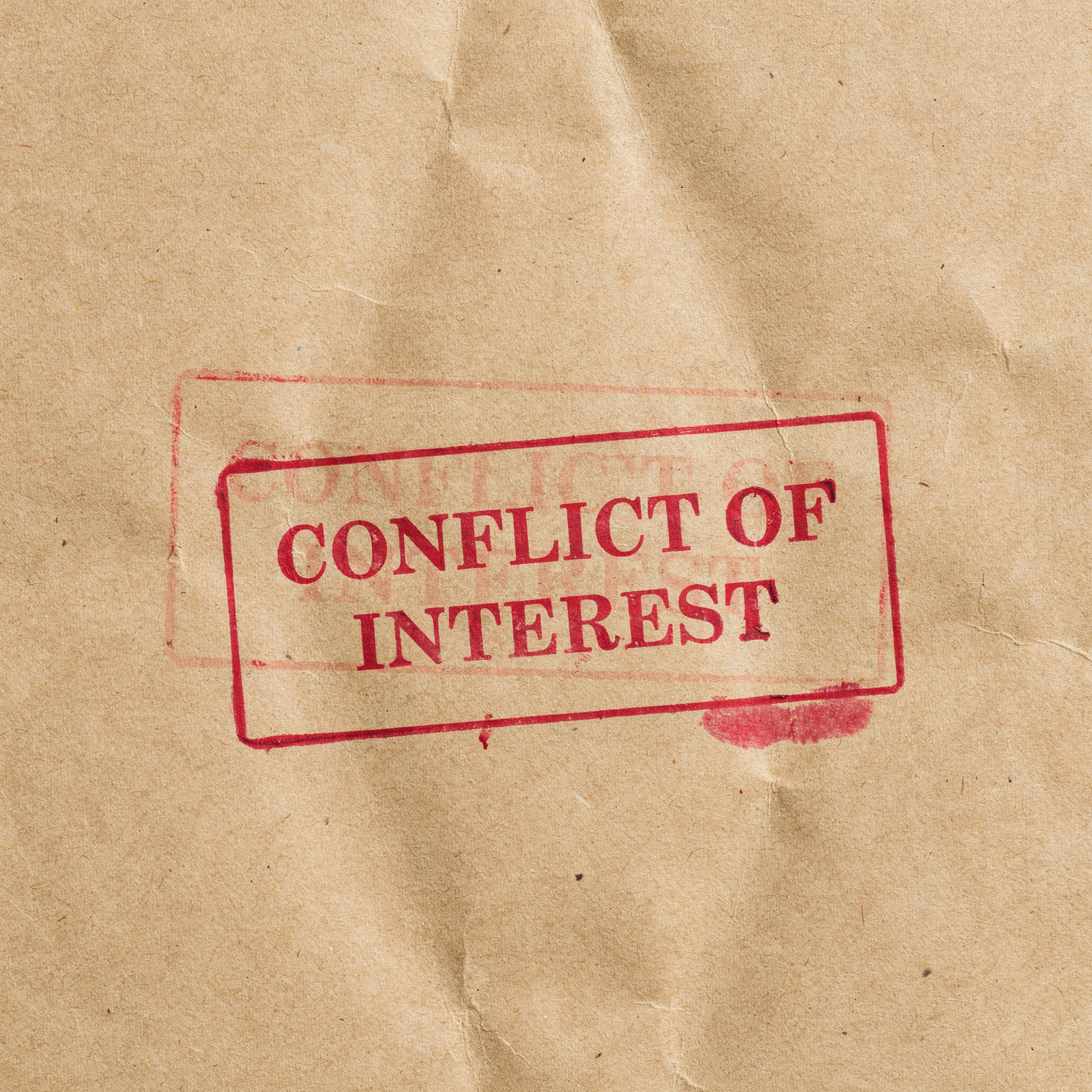 "conflict of interest" stamped in red on brown paper